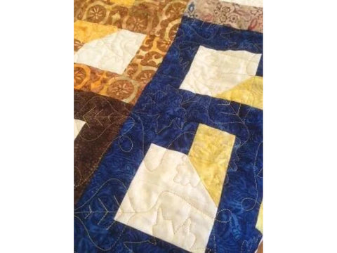 A close-up of a quilted fabric with blue, brown, yellow, and cream patterns.