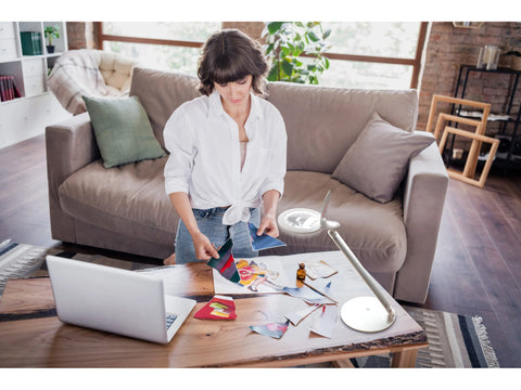 Daylight Halo Go Rechargeable Magnifier on a wooden table with a woman crafting.