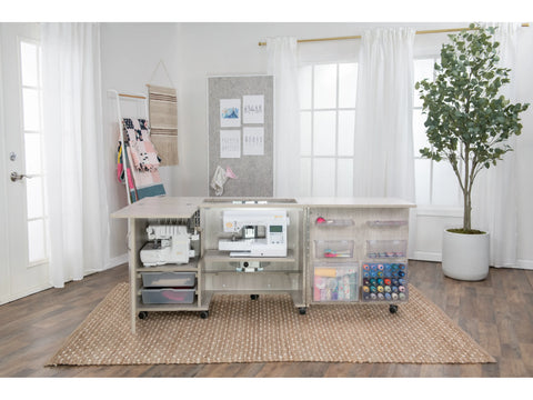 A light wood sewing cabinet with two sewing machines and craft supplies.