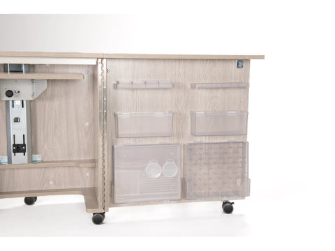 A light wood sewing cabinet with storage compartments and wheels.