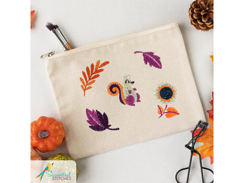A beige zippered pouch with embroidered autumn leaves, a squirrel, and a sunflower.