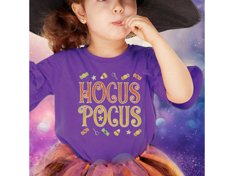 A young girl in a witch hat and purple "Hocus Pocus" shirt with candy designs.