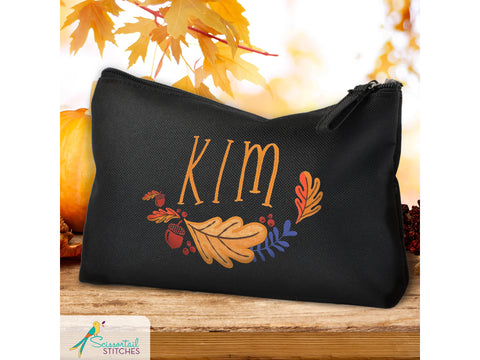 Black pouch with "KIM" and a fall leaf and acorn wreath design.