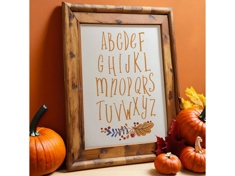 A framed alphabet print with fall foliage and pumpkins.