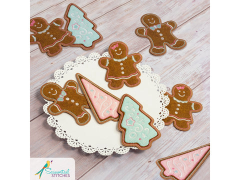 Embroidered gingerbread men and trees are arranged on a white doily.