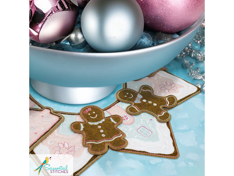 A light blue bowl filled with pink and silver ornaments sits above gingerbread-themed coasters.