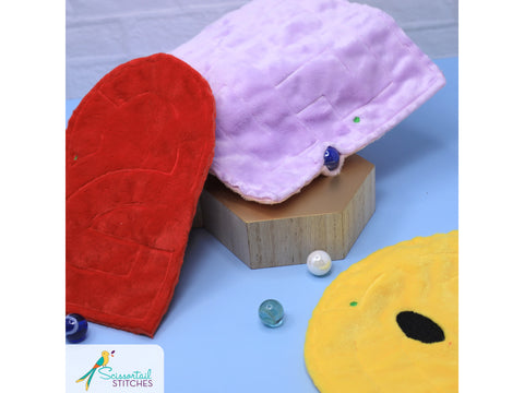 Three plush, colorful maze toys are displayed with marbles.