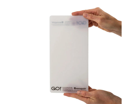 A person holds a translucent AccuQuilt GO! 5" x 10" cutting mat.