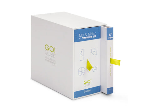 White AccuQuilt Qube Companion Corners 4" set with a yellow ribbon bookmark.
