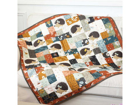 A quilted blanket with hedgehog appliques and various patterned fabric squares.