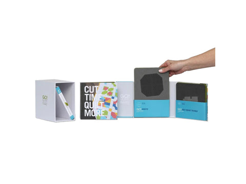A hand places a gray cutting die into a white storage box with other quilting supplies.