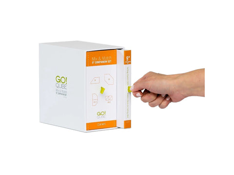 A hand pulls a white box with orange accents from a larger white box.