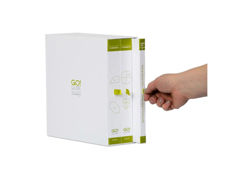 A hand pulls a white box set with green accents from a larger white box.