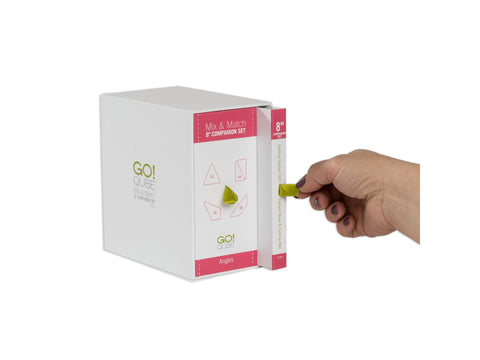 A hand pulls a green ribbon from a white box labeled "GO! QUBE Mix & Match 8" Companion Set Angles."