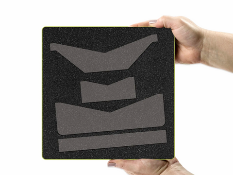 A person holds a black foam die-cutting board with four gray wallet-shaped dies.