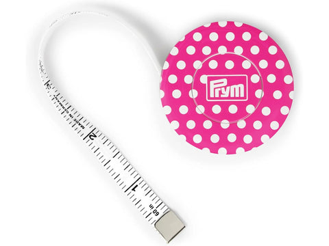 A pink polka dot Prym Love magnetic tape measure with a white tape extended.