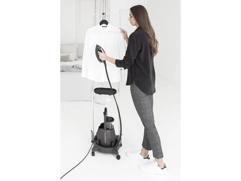 A woman steams a white shirt on a black Laurastar steam cart.