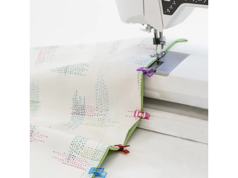 Prym Love Fabric Clips hold patterned fabric to a sewing machine.