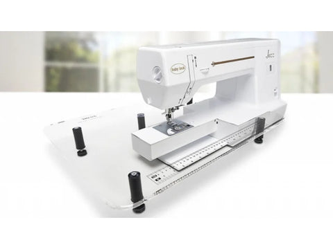 A white Baby Lock Jazz sewing machine sits on a clear acrylic extension table.