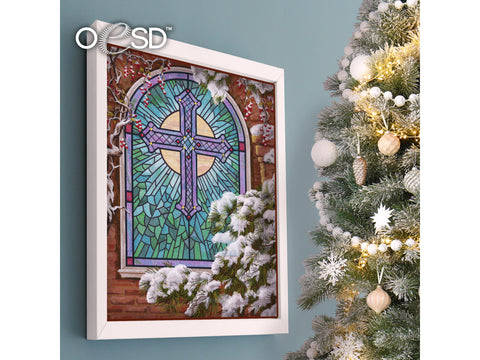 A framed OESD Christmas Church Window tiling scene hangs next to a decorated Christmas tree.
