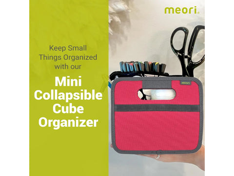A berry pink Meori mini collapsible cube organizer is held in a hand.