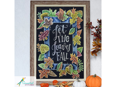 A framed chalkboard art piece with colorful autumn leaves and the phrase "Let the Leaves Fall."