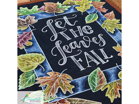 A black fabric panel with embroidered autumn leaves and the phrase "Let the Leaves Fall."