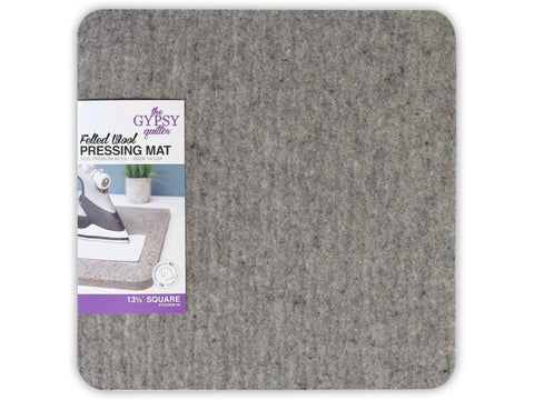 A gray felted wool pressing mat with a label showing an iron and product details.