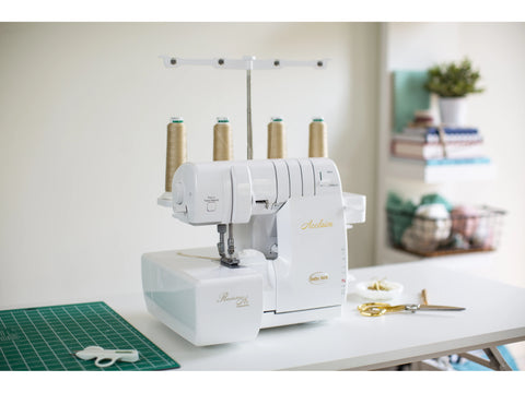 A white Baby Lock Acclaim serger with four spools of tan thread sits on a white table.
