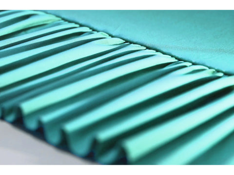 Close-up of teal fabric with evenly spaced pleats.