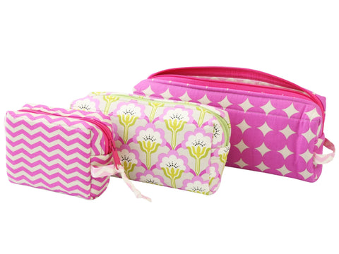 Three pink and white patterned cosmetic bags of varying sizes.