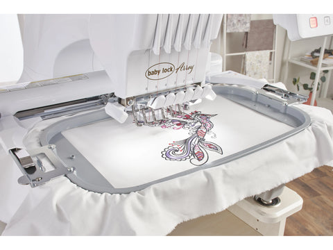 A white Baby Lock Array 6-needle embroidery machine is actively embroidering a colorful design.