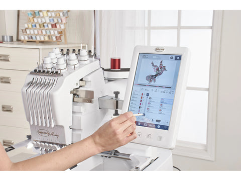 A person uses a stylus on the touchscreen of a white Baby Lock Array 6-needle embroidery machine.