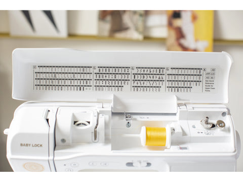 A white Baby Lock Brilliant sewing machine with a yellow spool of thread.