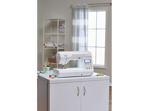 Baby Lock Lyric sewing and quilting machine on a white cabinet in a bright room.
