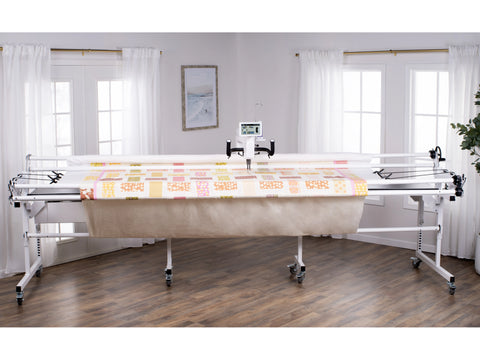 A white Baby Lock Regalia long arm quilting machine on a 10-foot frame with a quilt.