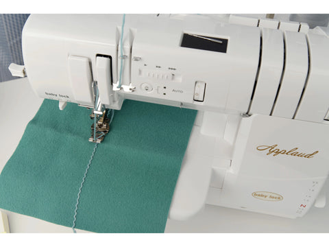 A white Baby Lock Applaud serger is shown with teal fabric and light blue thread.