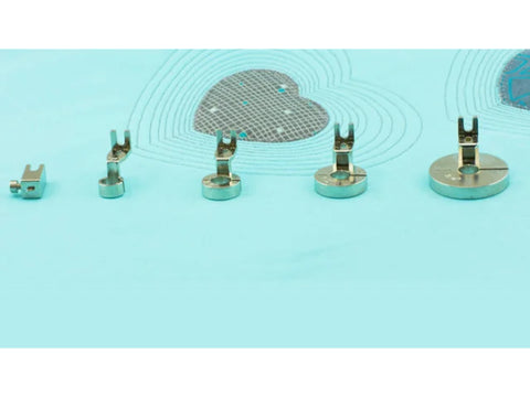 Five metal sewing machine presser feet are arranged on a light blue surface.