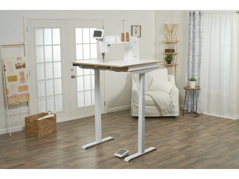 A white Baby Lock Regalia quilting machine sits on a height-adjustable lift table.
