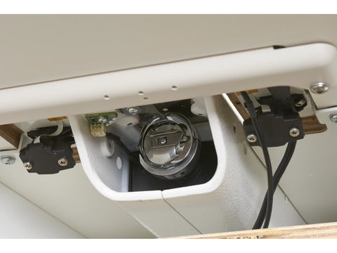 A close-up view of the bobbin area of a sewing machine with wires and components.