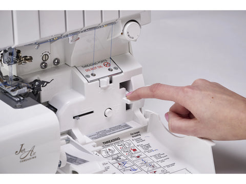 A hand presses a lever on a white Baby Lock Victory serger with JetAir Threading.