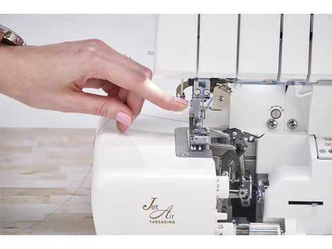 A person's hand threads a white Baby Lock Victory serger with Jet Air Threading.