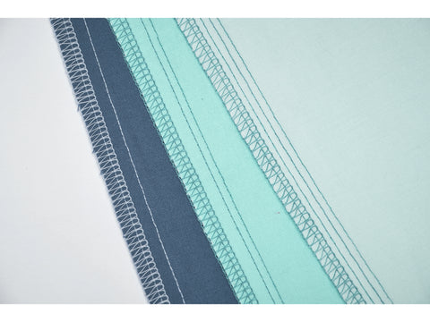 A close-up of fabric with various serged seams in different colors.
