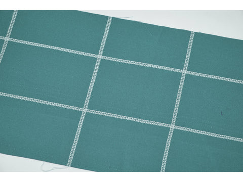 A teal fabric swatch with white grid-like stitching.