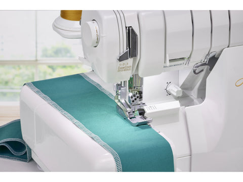 A white Baby Lock Accolade serger sewing a teal fabric with white thread.