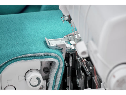 A close-up of a Baby Lock Accolade serger stitching teal fabric.