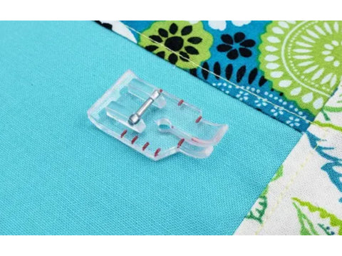 A clear 1/4 inch quilting foot is positioned on a turquoise fabric next to a patterned fabric.