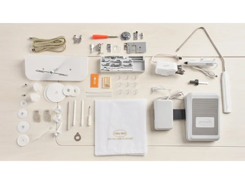 A collection of sewing machine accessories, including a foot pedal, power cord, and various tools, laid out on a light-colored surface.