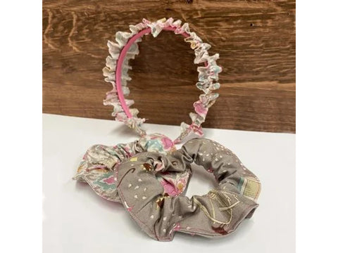 A pink headband with a ruffled floral fabric trim and two matching scrunchies.