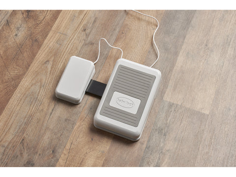 Baby Lock Ballad sewing machine foot pedal and power supply on a wooden floor.